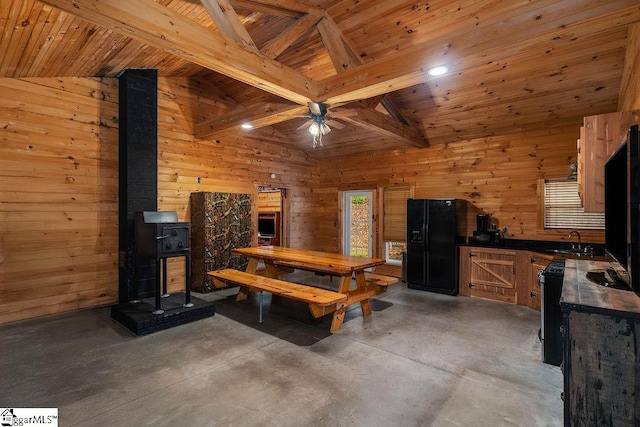 dining area featuring beam ceiling, wood walls, sink, wooden ceiling, and ceiling fan