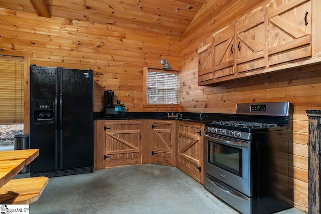 kitchen with black fridge, wood walls, vaulted ceiling, stainless steel range with gas stovetop, and wooden ceiling