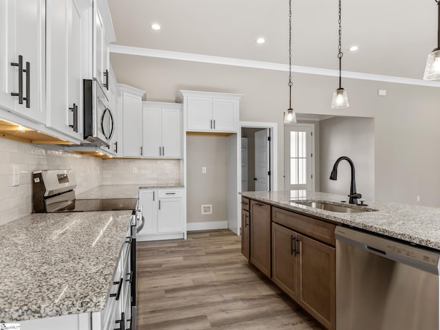 kitchen with a center island with sink, white cabinetry, sink, and appliances with stainless steel finishes