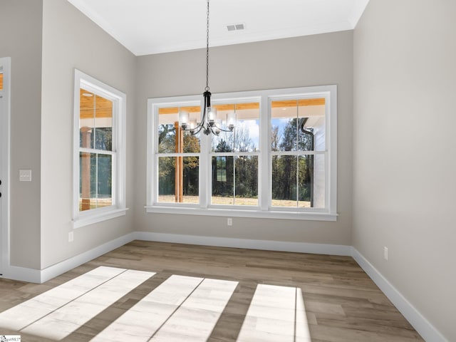 unfurnished dining area featuring light wood-type flooring and an inviting chandelier