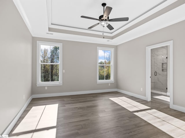 unfurnished bedroom featuring ceiling fan, ensuite bath, wood-type flooring, and multiple windows