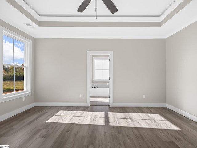 empty room featuring ceiling fan, wood-type flooring, a raised ceiling, and crown molding