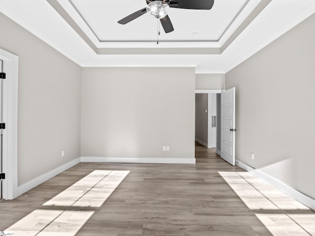 unfurnished bedroom featuring ceiling fan, light hardwood / wood-style flooring, crown molding, and a tray ceiling