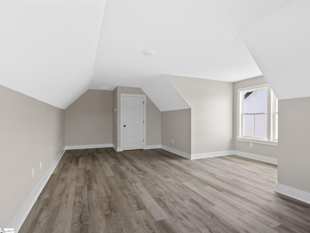 additional living space featuring wood-type flooring and vaulted ceiling