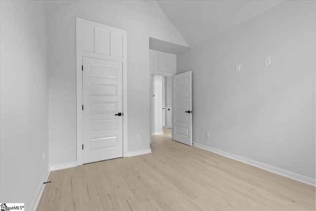 unfurnished bedroom featuring light hardwood / wood-style flooring and lofted ceiling