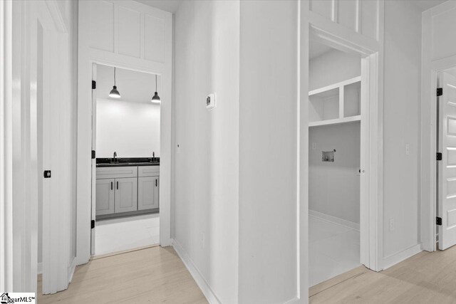 hallway with sink and light hardwood / wood-style floors