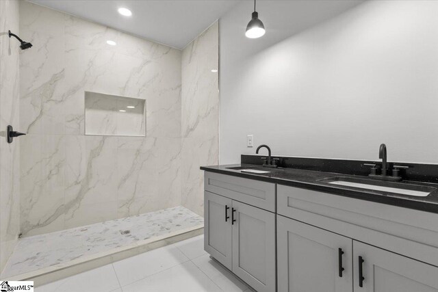 bathroom with tile patterned flooring, vanity, and a tile shower