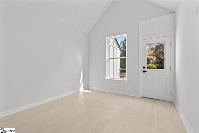 interior space with light hardwood / wood-style floors and high vaulted ceiling