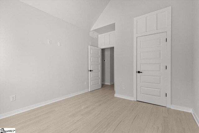 unfurnished bedroom with light wood-type flooring and lofted ceiling