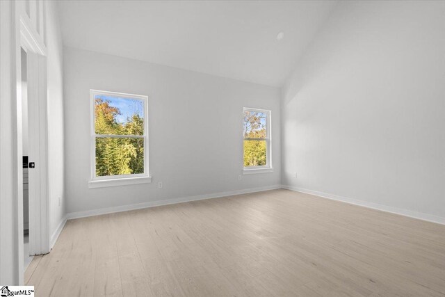 empty room with vaulted ceiling and light wood-type flooring