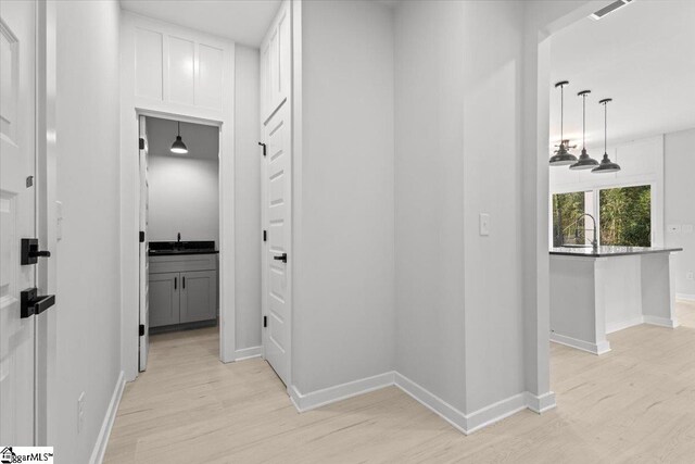 corridor featuring light wood-type flooring and sink