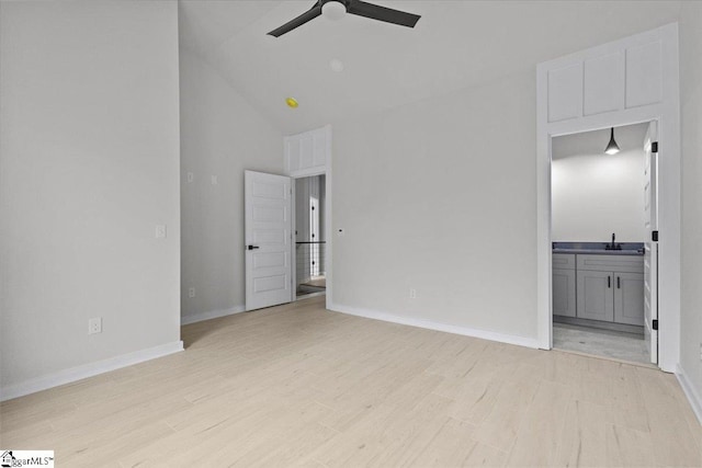 unfurnished living room with ceiling fan, sink, high vaulted ceiling, and light hardwood / wood-style flooring