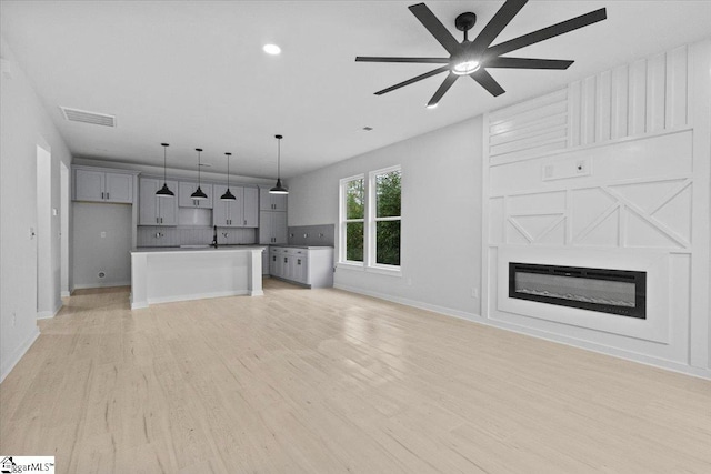 unfurnished living room with ceiling fan, light hardwood / wood-style flooring, and sink