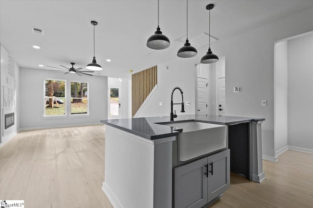 kitchen featuring ceiling fan, light hardwood / wood-style flooring, sink, and an island with sink