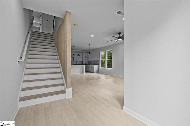 stairs featuring hardwood / wood-style floors and ceiling fan