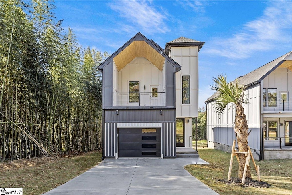 view of front of home featuring a balcony, a front yard, and a garage