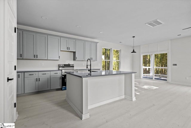 kitchen featuring stainless steel electric range oven, a center island with sink, light hardwood / wood-style flooring, and sink