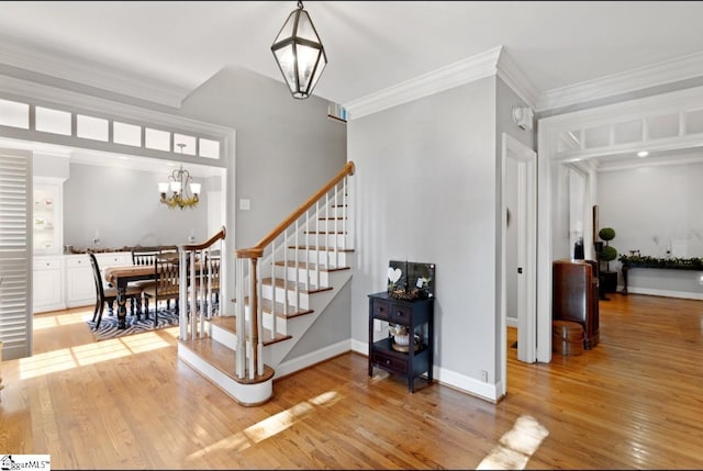 stairs with ornamental molding, a notable chandelier, and hardwood / wood-style flooring