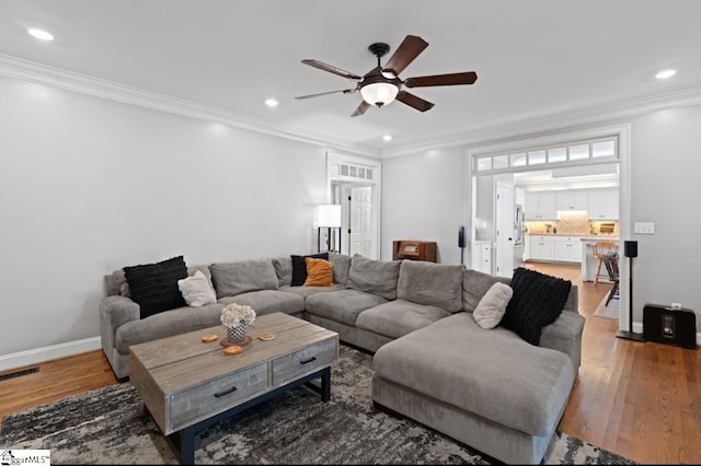 living room featuring hardwood / wood-style flooring, ceiling fan, and crown molding