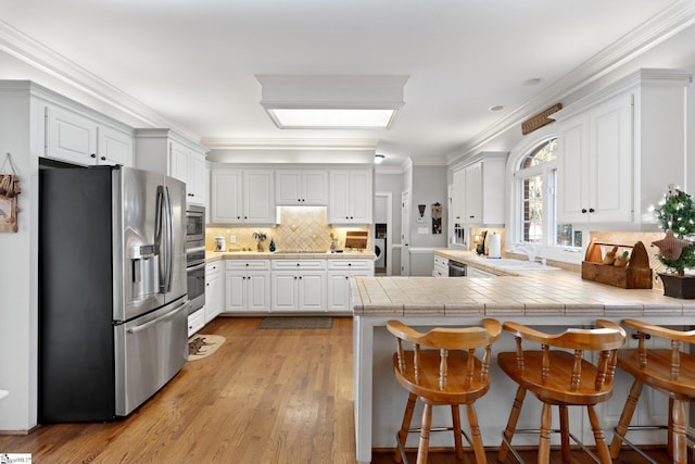 kitchen featuring light hardwood / wood-style flooring, white cabinetry, kitchen peninsula, and stainless steel appliances