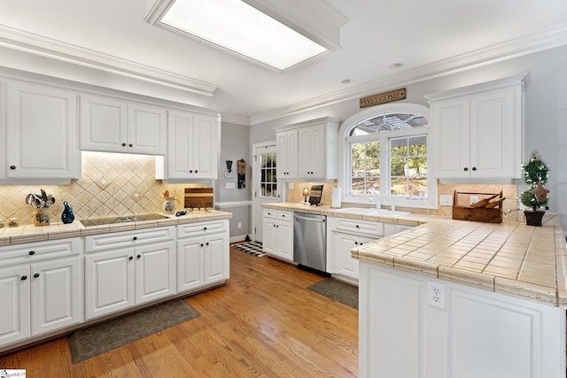 kitchen with crown molding, white cabinetry, light wood-type flooring, tile counters, and stainless steel dishwasher