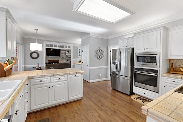 kitchen with decorative light fixtures, white cabinetry, appliances with stainless steel finishes, and tile counters