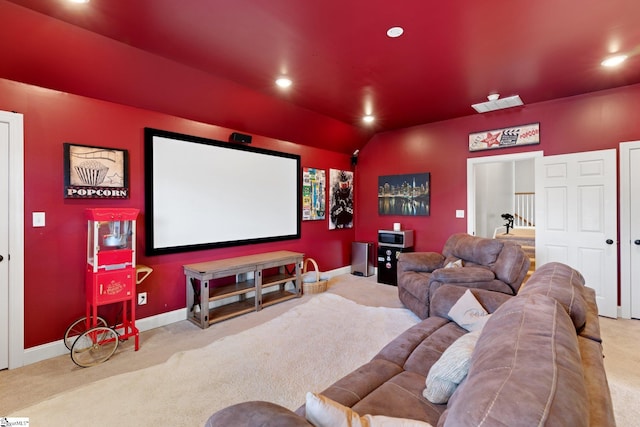 carpeted cinema room with vaulted ceiling