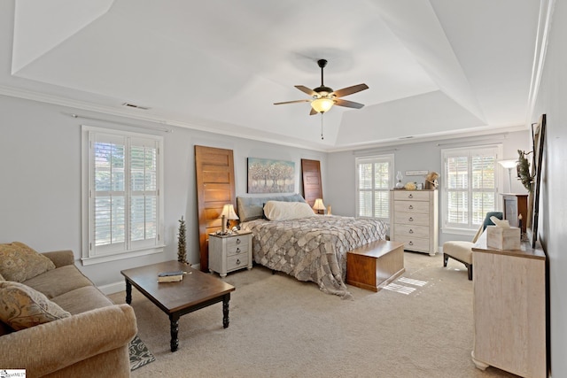 bedroom featuring light colored carpet, ceiling fan, crown molding, and a tray ceiling