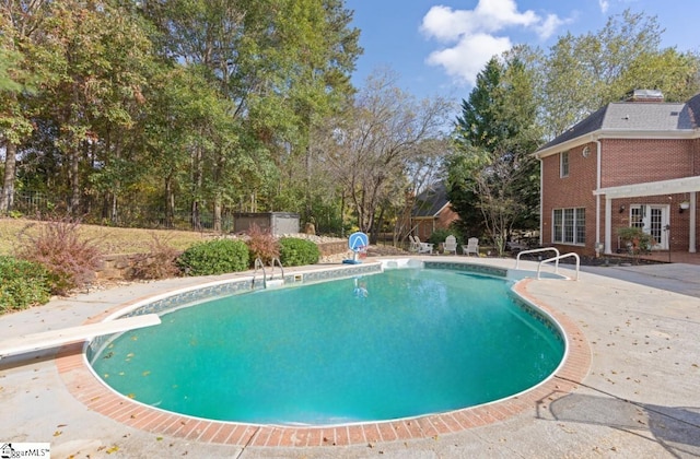 view of pool with a patio and a diving board