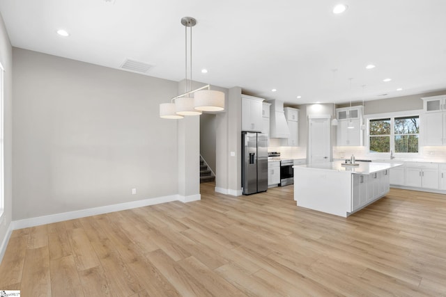 kitchen with white cabinetry, light wood-type flooring, appliances with stainless steel finishes, and decorative light fixtures