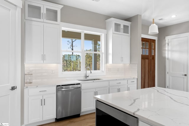 kitchen featuring stainless steel dishwasher, white cabinetry, decorative light fixtures, and backsplash