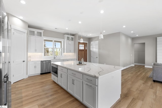 kitchen featuring stainless steel appliances, light hardwood / wood-style floors, white cabinetry, and a center island