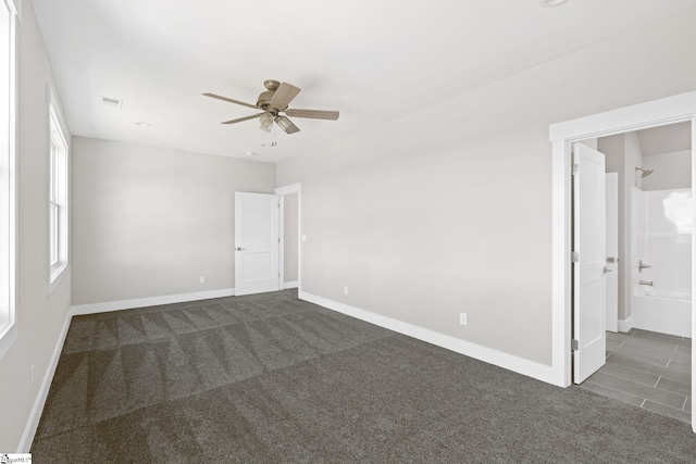 empty room with ceiling fan and dark colored carpet