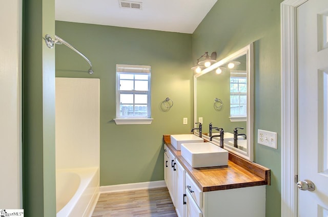 bathroom featuring vanity, a wealth of natural light, wood-type flooring, and shower / washtub combination