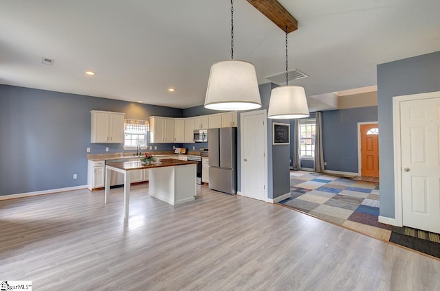 kitchen with light hardwood / wood-style flooring, a center island, a wealth of natural light, and stainless steel appliances