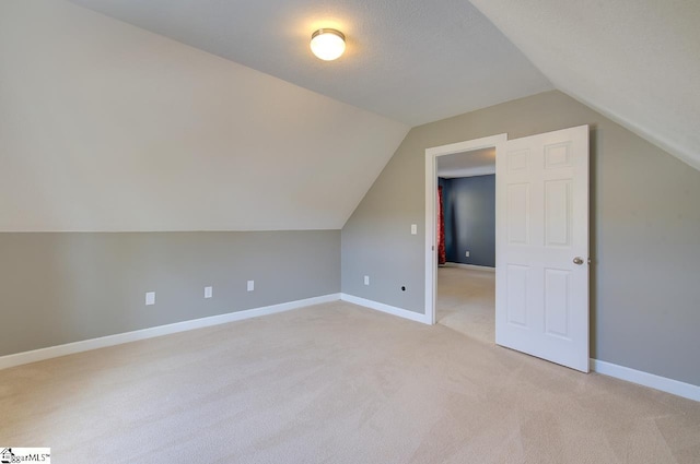 bonus room featuring light colored carpet, a textured ceiling, and lofted ceiling