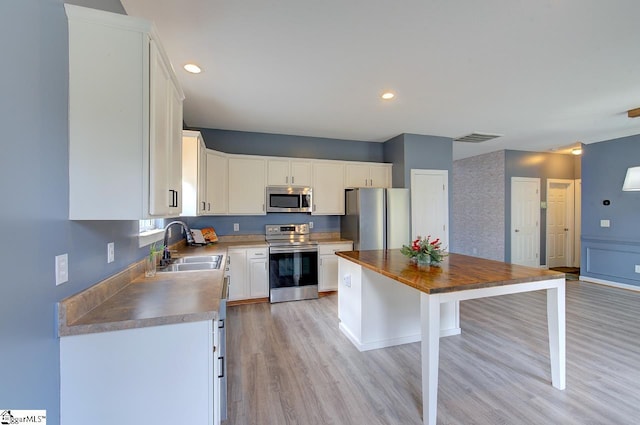 kitchen with light hardwood / wood-style floors, white cabinetry, sink, and appliances with stainless steel finishes