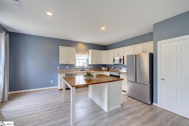 kitchen with light wood-type flooring, white cabinetry, a center island, and stainless steel appliances