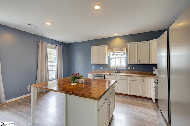 kitchen featuring appliances with stainless steel finishes, wood counters, a healthy amount of sunlight, and a center island