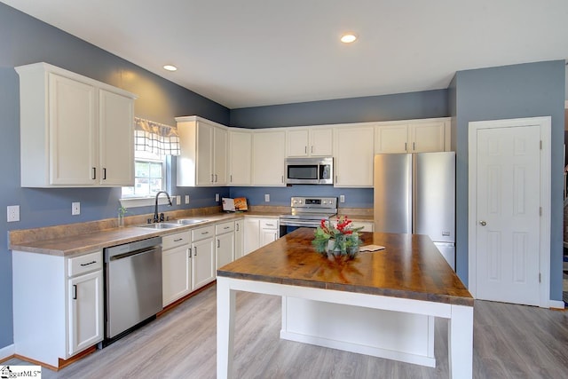 kitchen with white cabinets, light hardwood / wood-style floors, stainless steel appliances, and sink