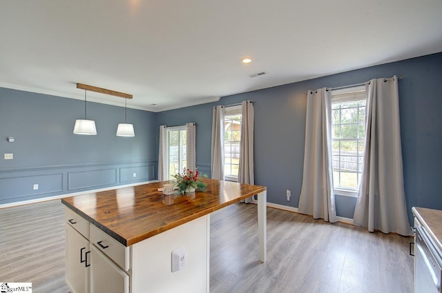 kitchen with white cabinets, a wealth of natural light, wooden counters, and decorative light fixtures