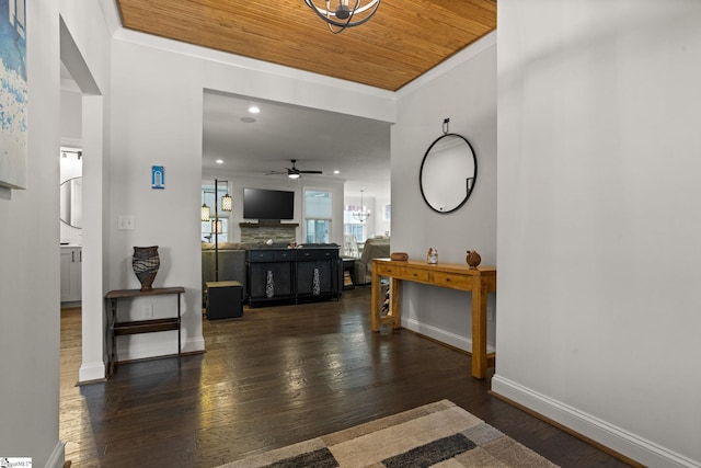 foyer entrance with ceiling fan with notable chandelier, wooden ceiling, dark hardwood / wood-style floors, and crown molding