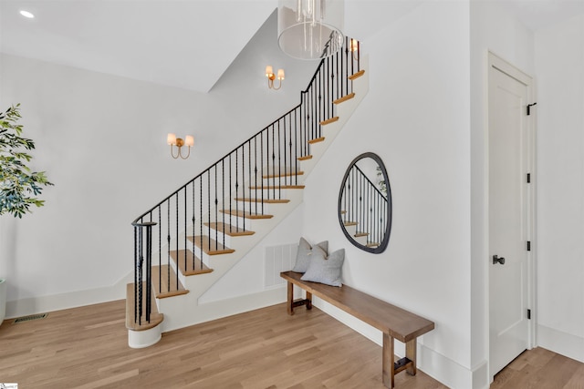 stairs featuring hardwood / wood-style floors and a chandelier