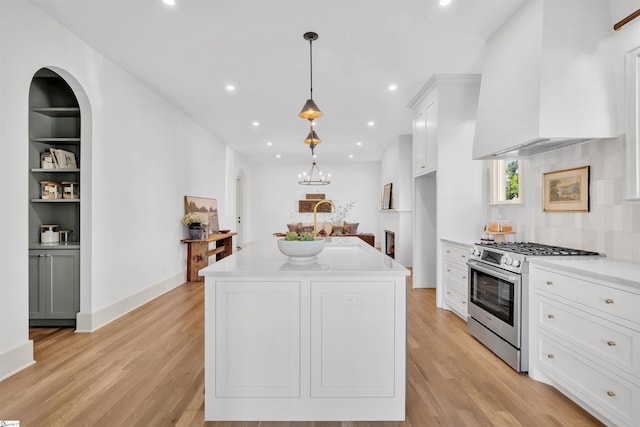 kitchen featuring pendant lighting, white cabinets, stainless steel range, and light wood-type flooring