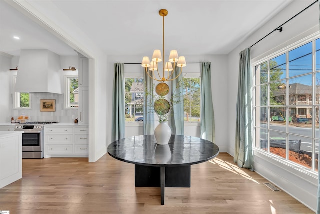 dining room featuring light hardwood / wood-style flooring, a notable chandelier, and a healthy amount of sunlight