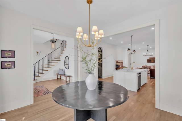 dining space with a chandelier, sink, and light hardwood / wood-style flooring