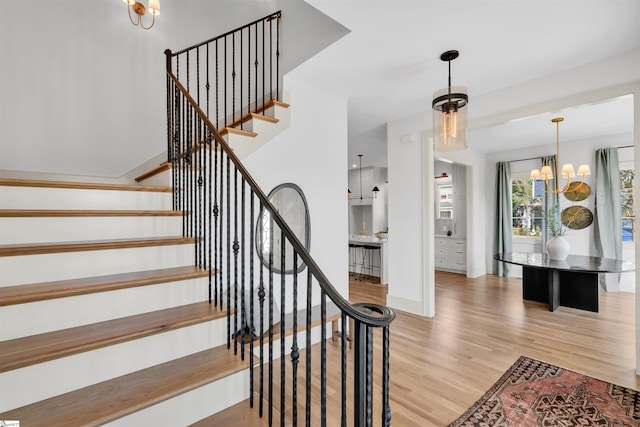 staircase with hardwood / wood-style flooring and a chandelier