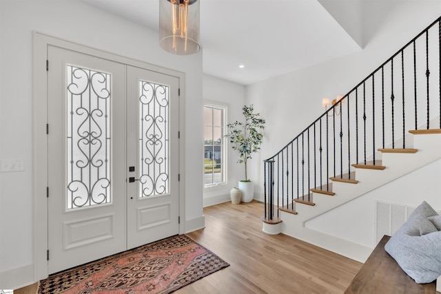 foyer entrance with french doors and light hardwood / wood-style floors