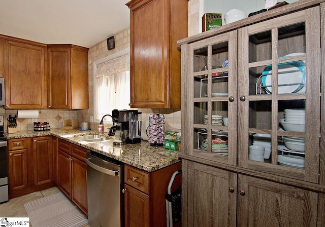 kitchen with light tile patterned floors, light stone countertops, decorative backsplash, sink, and dishwasher