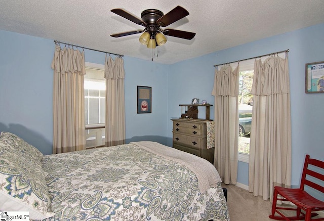 bedroom featuring carpet flooring, a textured ceiling, multiple windows, and ceiling fan